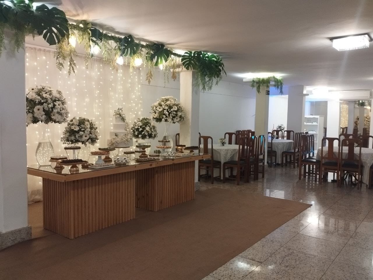 Salão da Maison Orange Classique com mesa de doces e mesas de convidados em Vitória ES