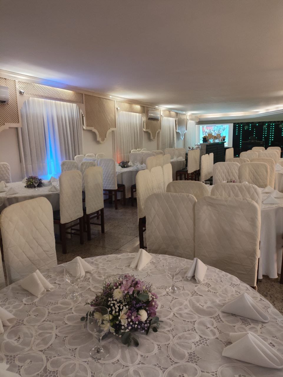 Salão da Maison Orange Classique preparado com mesas redondas para evento em Vitória ES